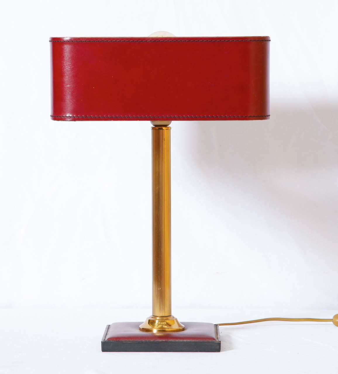 Jacques Adnet (1900 - 1984) designed this beautiful and useful table lamp shortly after World War II. Brass stem and saddled stitched blood red leather.