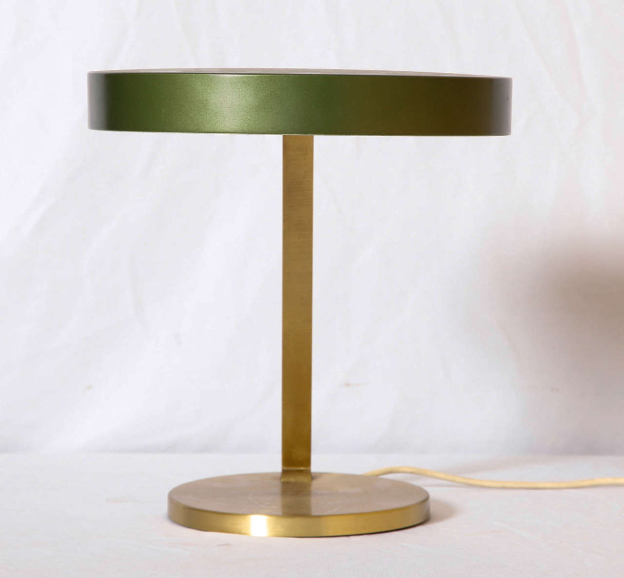 Adjustable desk lamp having an enameled emerald green shade connected by a curved brass stem and base, by Bauhaus designer Christian Dell.