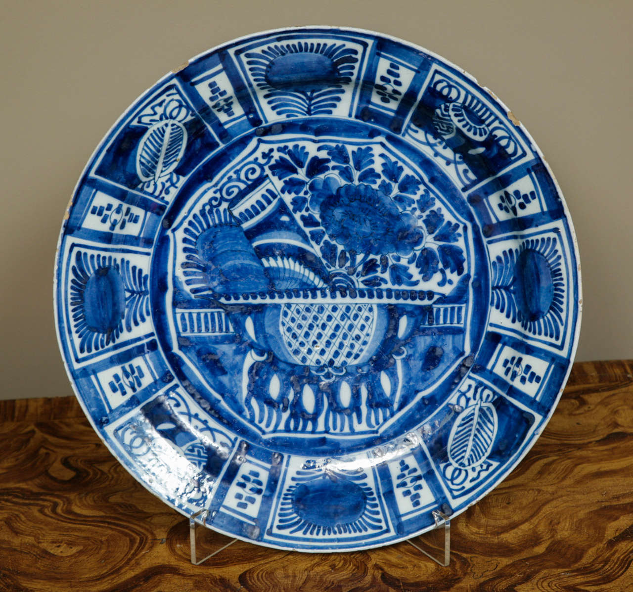A mid 18th century Delft blue and white charger painted in the kraak style, a bowl containing flowers, a gourd and a scroll central to radiating panels of Buddhist objects alternating with flowers. Very dark cobalt blue palette. Diameter 13.75 (35