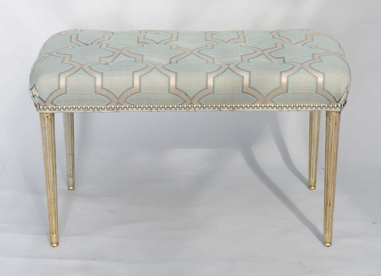 Bench, having a rectangular tufted seat finished with silver nailheads, raised on four round fluted tapering legs .