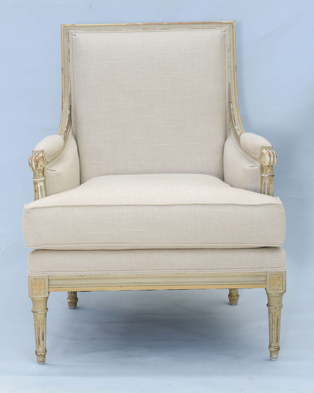 Pair of bergeres, distressed painted finish, each having upholstered square back, outswept arms with padded armrest, raised on round fluted legs; upholstered in linen fabric.