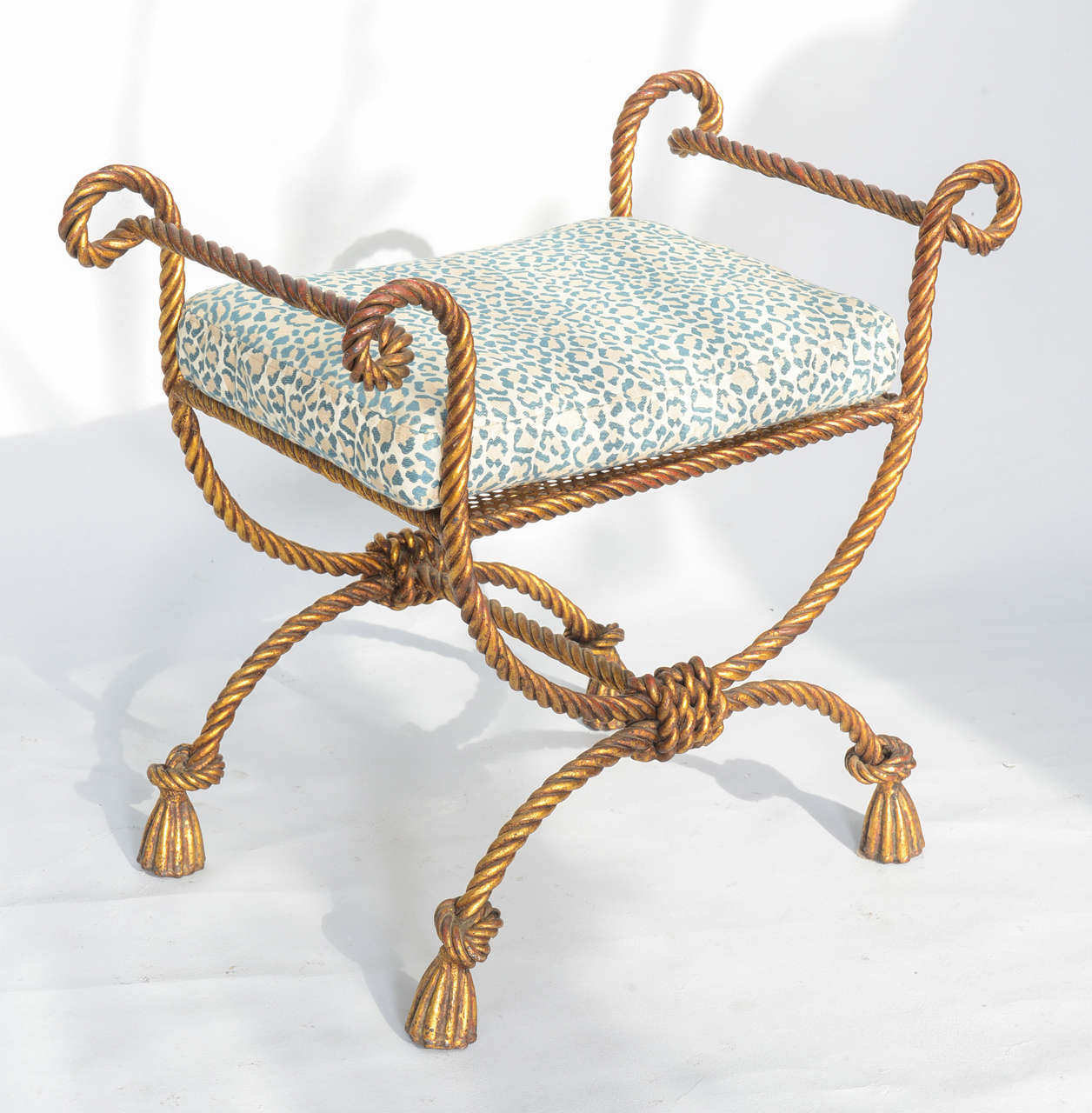 Vanity bench, by Niccolini, of heavy-gage gilded iron, fashioned as rope, having a rectangular cushion flanked by scrolling arms, on X-frame legs with rope-wrapped stretcher, terminating in tassel feet.

Stock ID: D1882