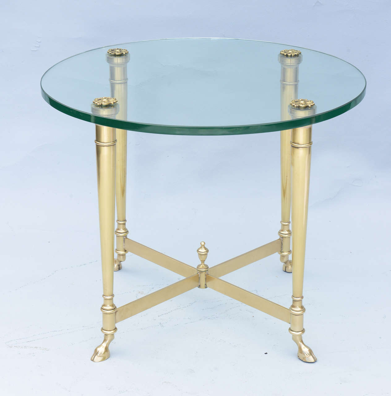 Jansen style, single side or end table, of polished brass, its round glass top secured to legs by rosettes, raised on round tapering legs, joined by X-stretcher, centered by a finial, terminating in hoofed feet.

Stock ID: D4365