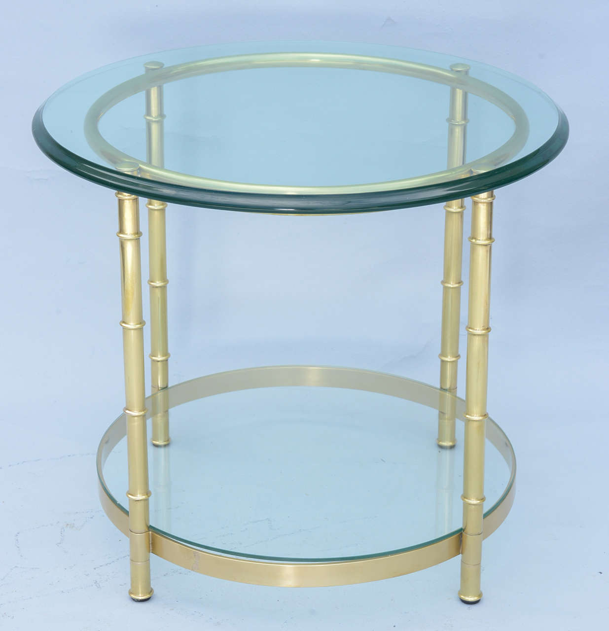 End or side table, of polished brass, its round glass top raised on faux bamboo legs, joined by ring apron and shelf-stretcher.

Stock ID: D7191