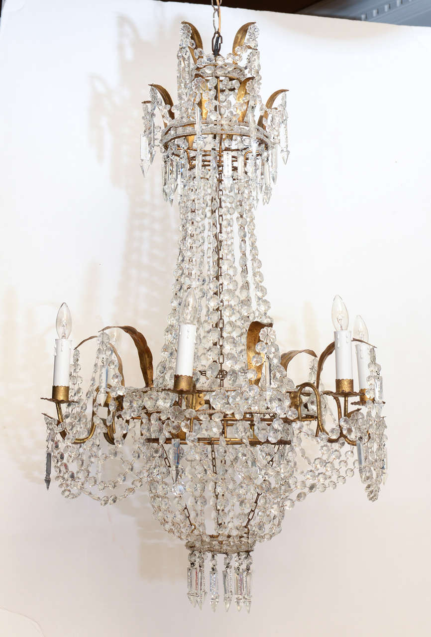 Chandelier, in beaded basket form, of gilded iron, surmounted by double crown with gilded leaves draped with beads and prisms, six scrolling candlearms; the entire fixture draped in beads and prisms.

Stock ID: D6741