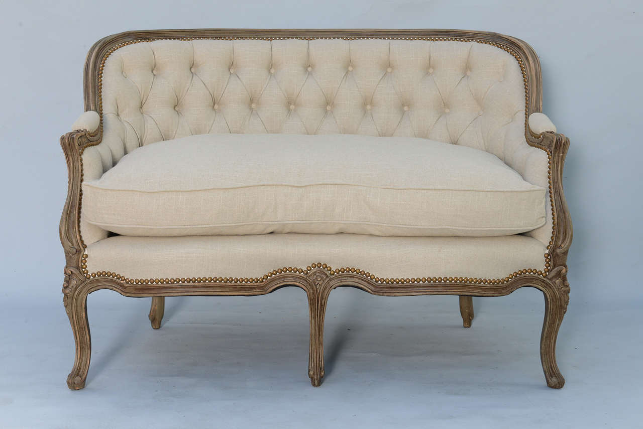 Settee, of walnut, in the Louis XV style, having a tufted padded back surmounted by a channeled crestrail, continuing to padded elbow rests, and finished by scrolling ends, on downsept terminals, its loose down cushion on serpentine apron, raised on