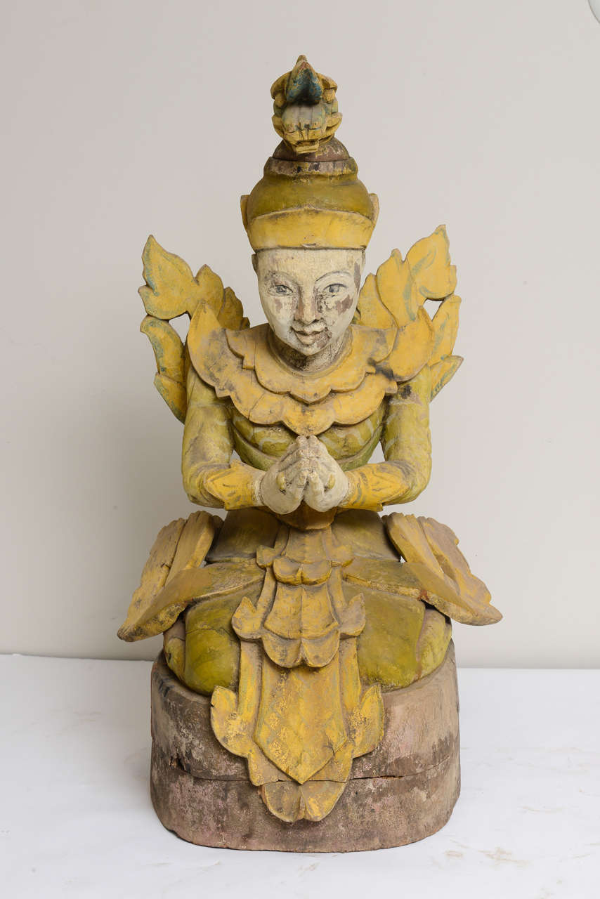 Hand carved and painted wooden sculpture of praying kneeling barefoot Asian Goddess with wings and a dragon head on top of Goddess' hat. The statue sits on top of the wooden pedestal. Circa 1850's
