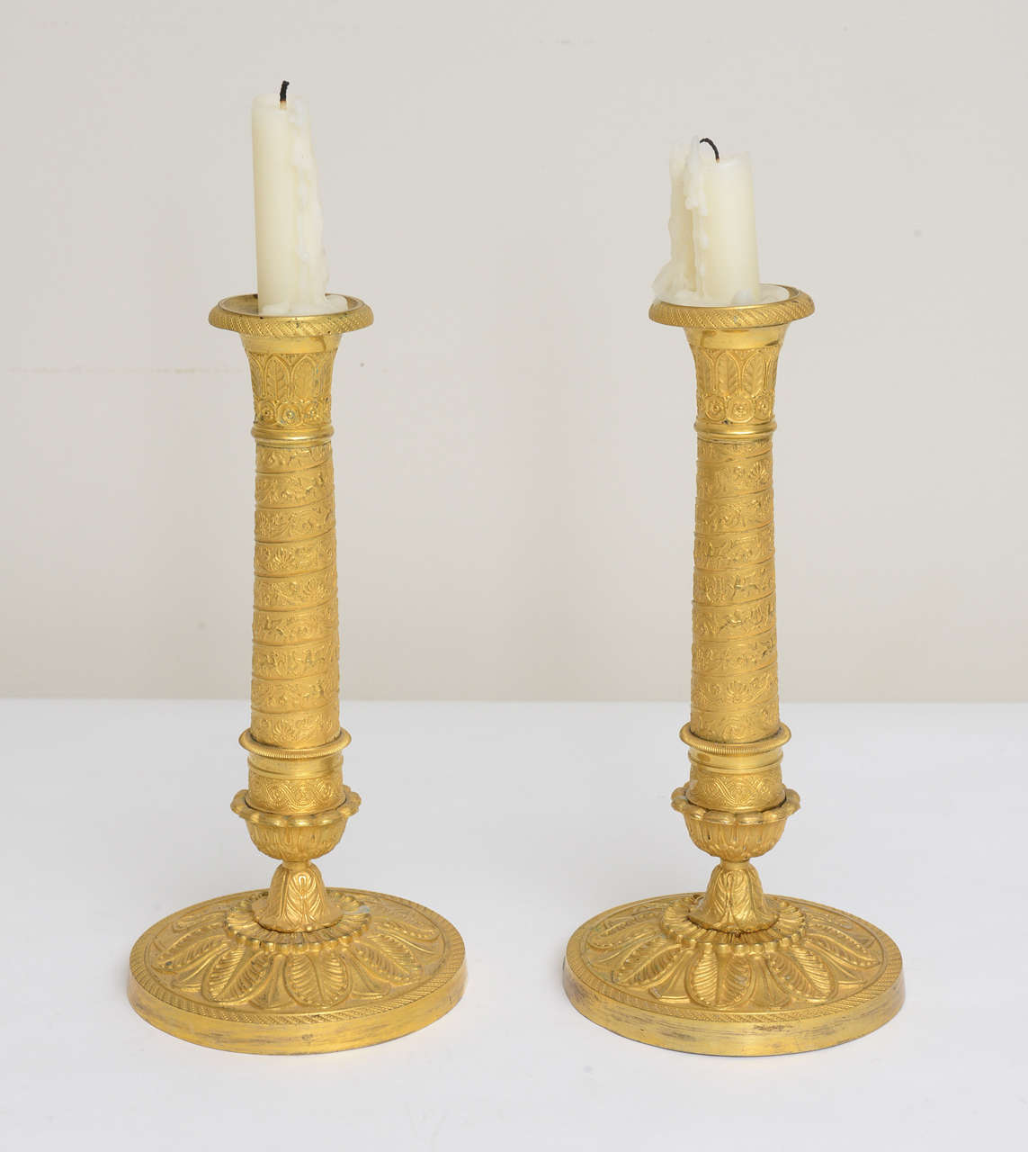 Pair of  gilt bronze and bronze doré candlesticks, finely engraved with acanthus leaves, lires and pegasus. French Empire period. Bobeches come off for easy cleaning of the wax.