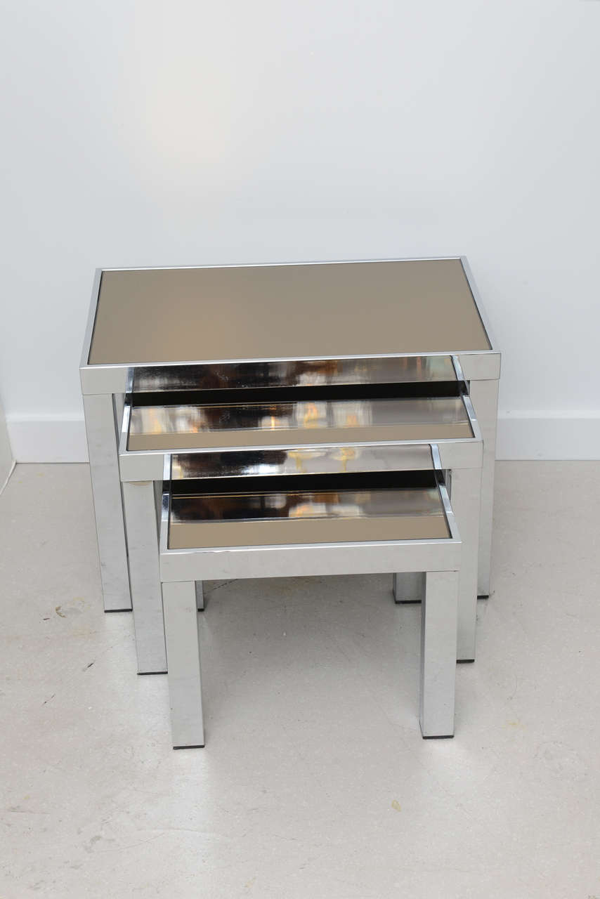 Vintage trio of nesting tables with chrome bodies and smoked glass tops.