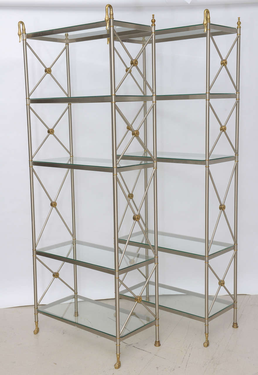 Pair of steel and brass etageres with swan motif and glass shelves.
