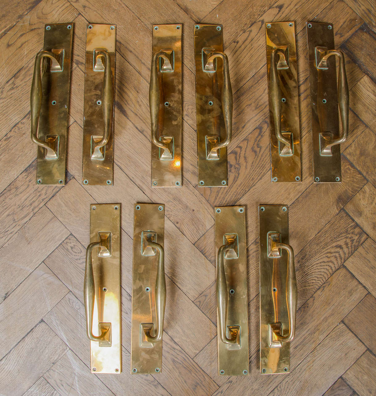Five pairs of matching antique door pulls in solid brass. These attractive polished brass door pull handles have a traditional design with an elegant shaped handle and plain rectangular plate. Late 19th Century.

Price is per pair.