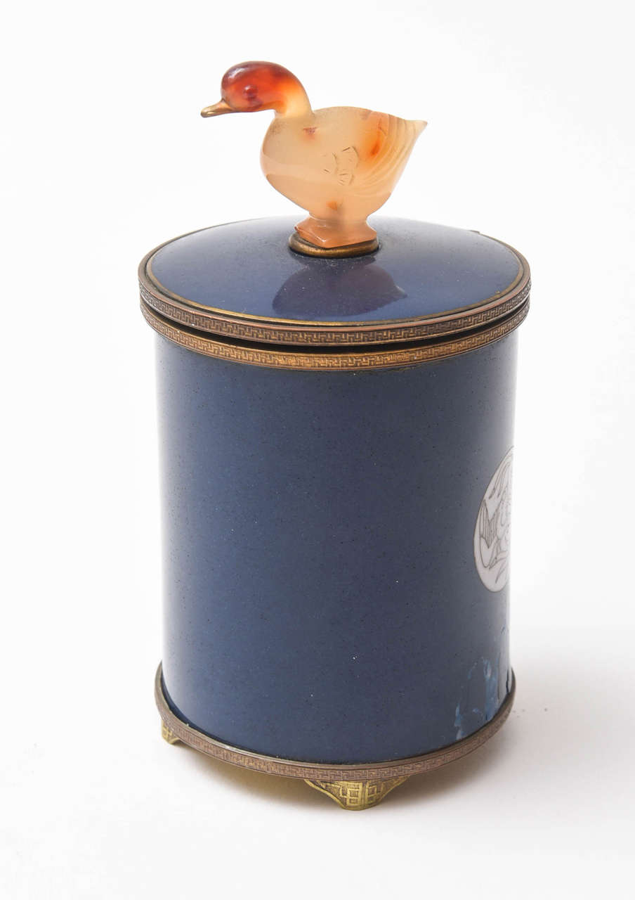Vintage enameled brass cigarette dispenser. Topped with a finely polished duck in agate. Lid is connected to a mechanism that pulls up the cigarettes to dispense.