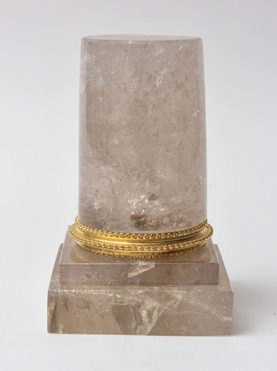 Partial rock crystal column on a double square base. Brass polished ring surrounds the base of the column.