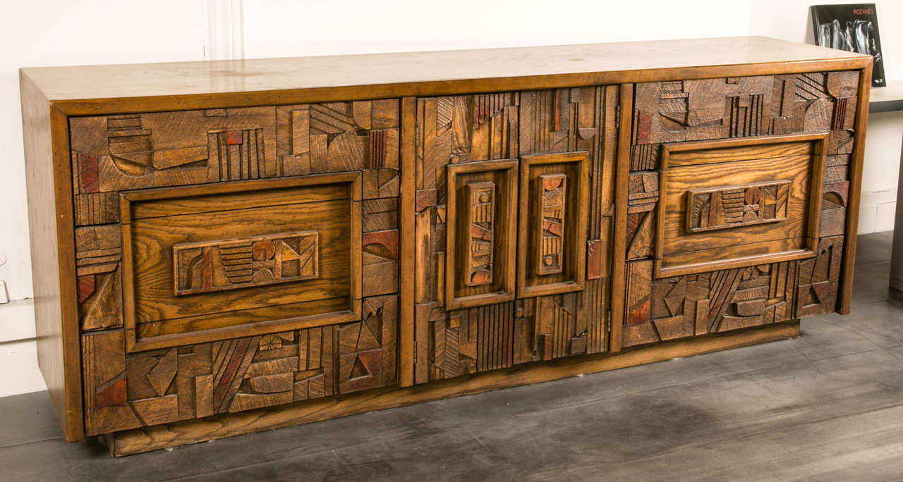 Sideboard by Lane as a sculpture.

circa 1970.
USA work
in style of Paul Evans.
Carved and red patinated oak
storage drawers whose central portion is opened by two leaves
stamped first left drawer.