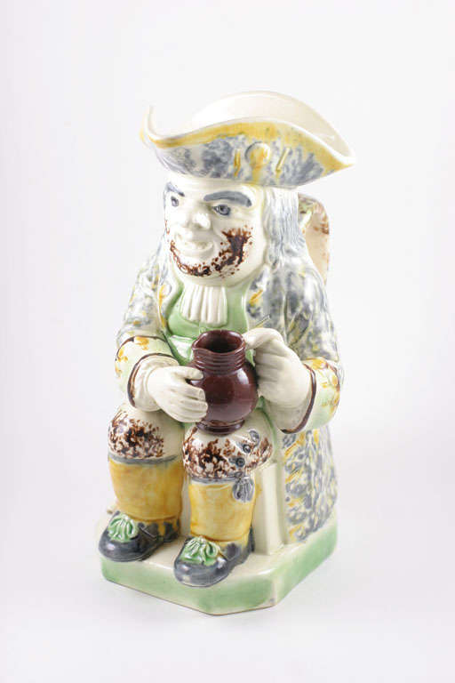 A rare English creamware bearded toby jug decorated in underglaze colors of yellow, brown and gray