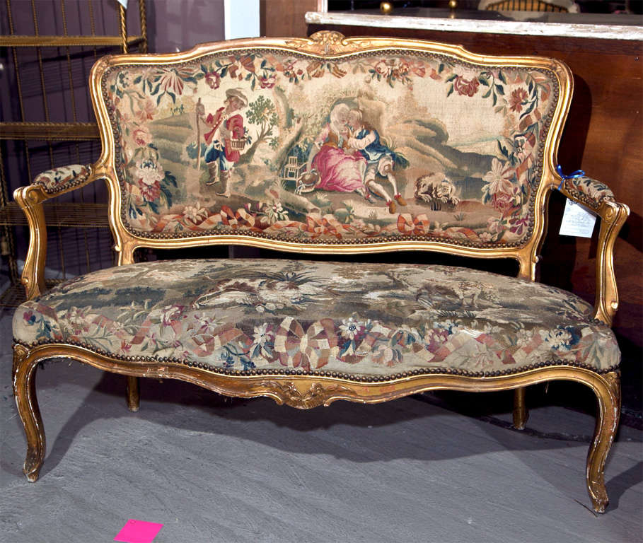An attractive French Louis XV style settee, circa 1930s, the shaped back and padded arms, upholstered in Aubusson tapestry and decorated with nail heads, raised on cabriole legs.