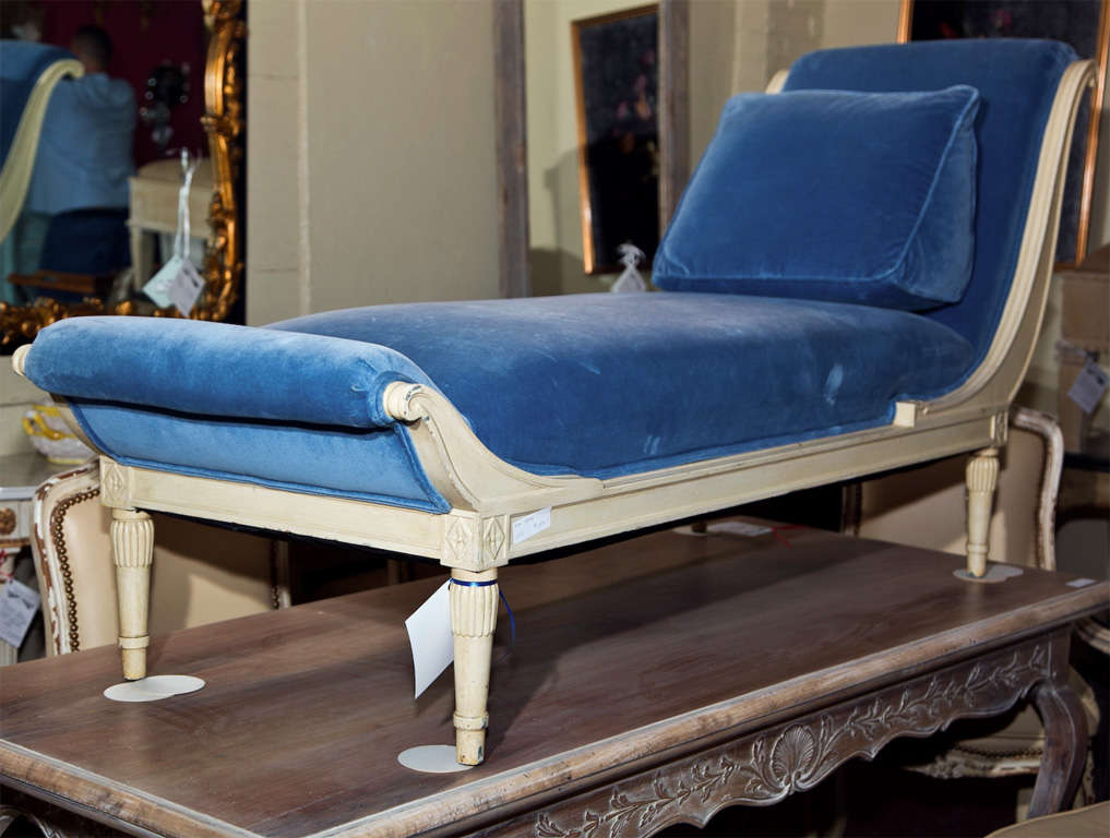 Attractive French creme peinte chaise lounge, 20th century, upholstered in blue velvet with a cushion pillow, raised on circular tapering legs.