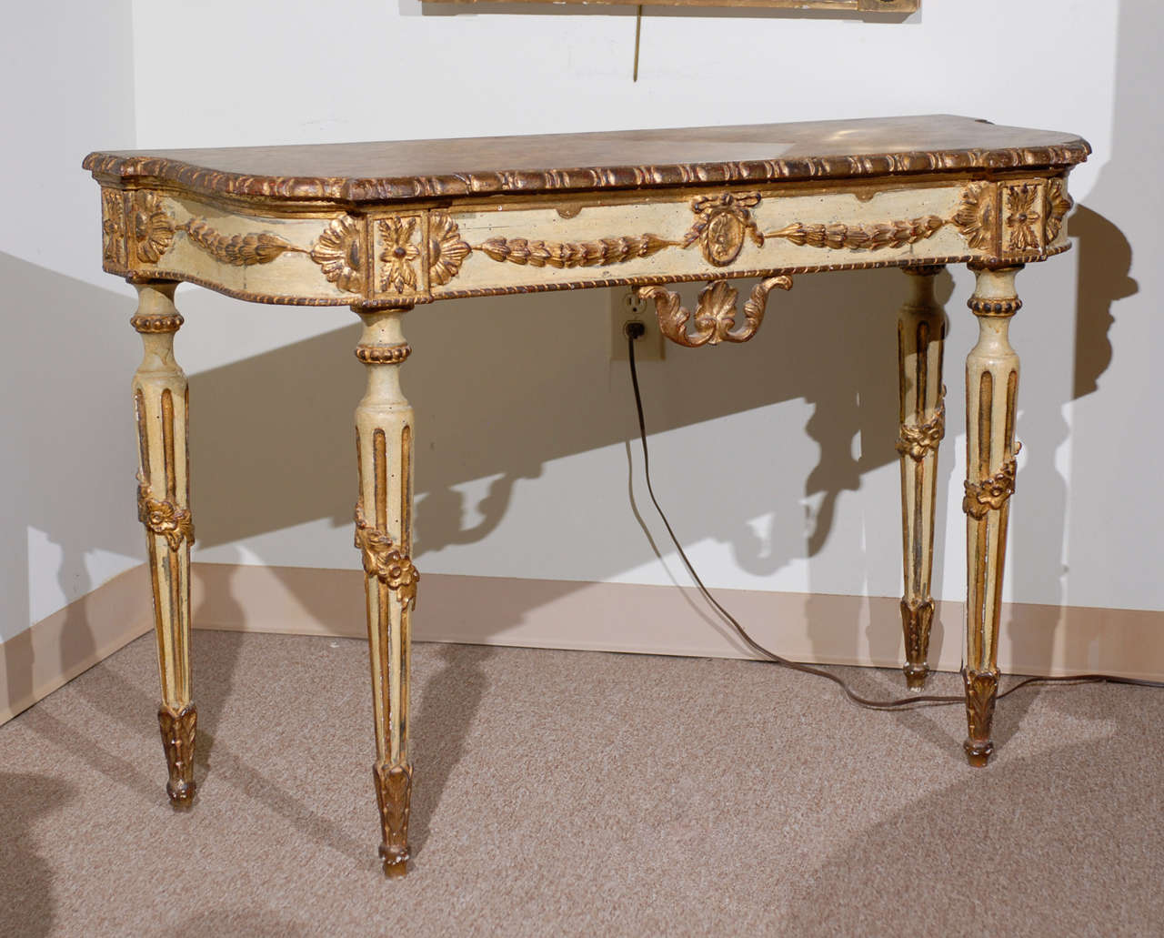 A Pair of Italian Neoclassical Style Painted and Parcel Gilt D-Shaped Console Tables with Faux Painted Marbleized Tops, Fluted Tapering Legs and Carved Flower and Swag Detail, first quarter of the 20th Century.
