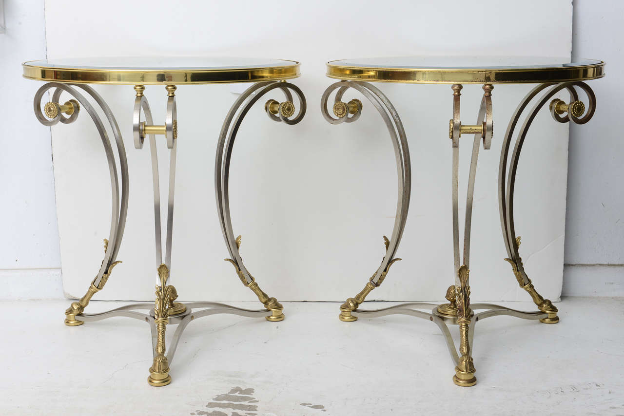 This handsome pair of side tables is very much in the style of pieces created by the iconic firm of Maison Jansen in the 1960s. They are fabricated in stainless steel, polished brass and an inset beveled-glass top.

Note: They can be purchased