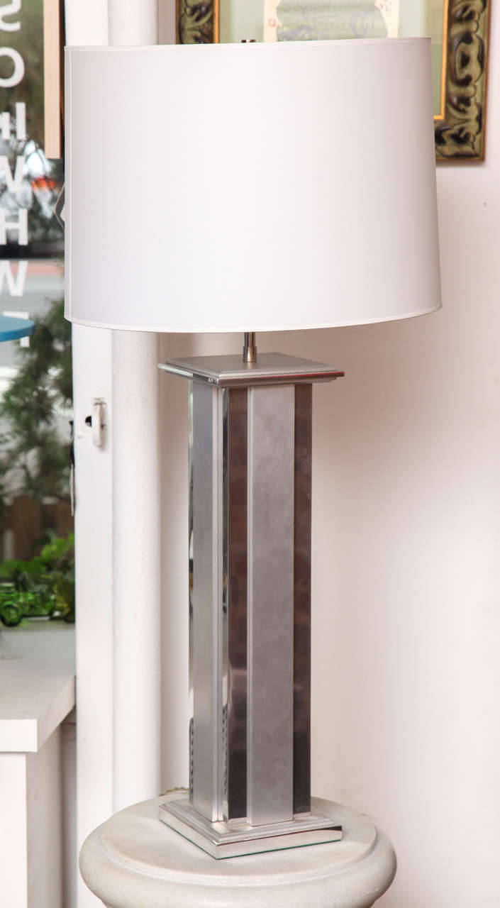 This classy Art Deco table lamp has a lined steel base that reflects the Chrysler Building's architecture in its combination of two metal finishes. It also has a white cylinder paper shade that complements the base. The shade was updated and
