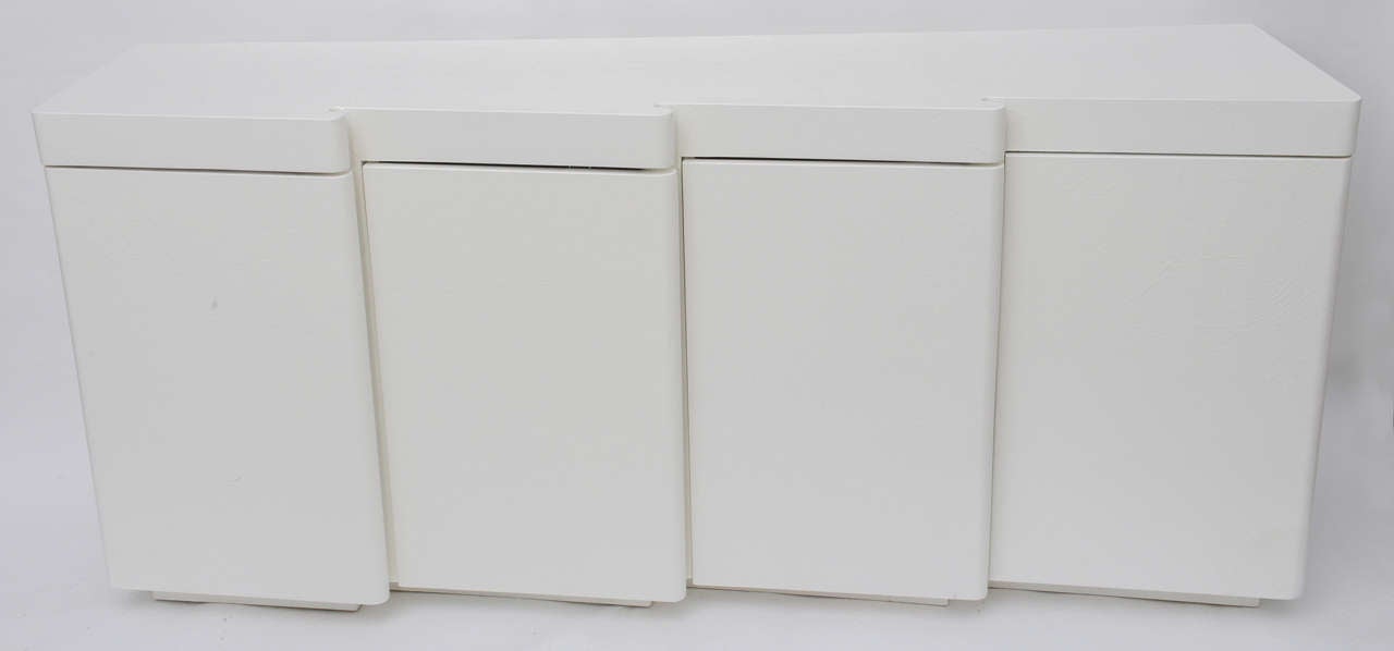 Unique credenza covered with a textured finish with a touch of plaster in it and completed in satin white lacquer maintaining the dead white plaster appearance. An invisible satin clear coat has been applied to protect the finish. Wood construction
