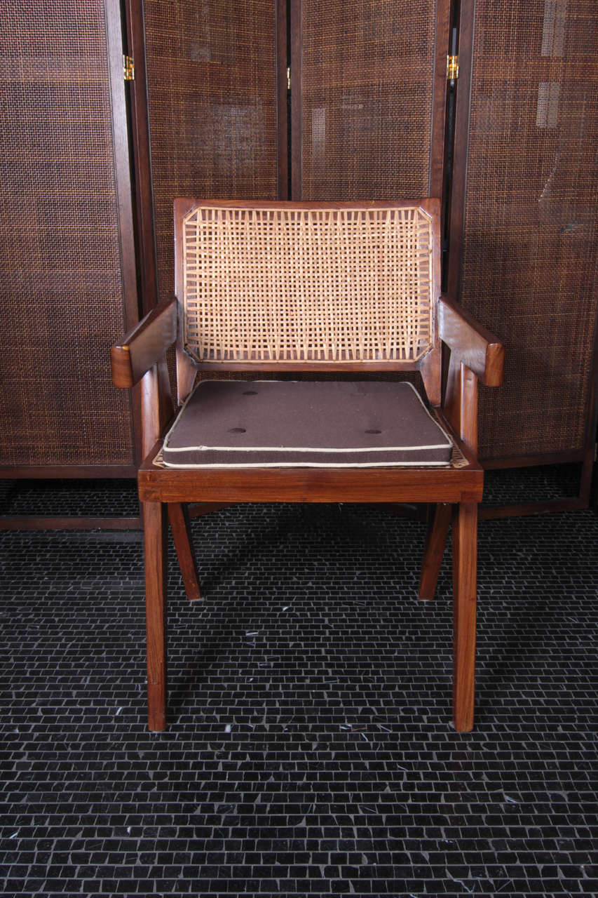 Conference armchair, 1952-56 by Pierre Jeanneret. This mid century modern armchair is crafted of solid teak with a raked, low caned backrest, square caned seat, tapered armrests and raised on scissor legs.