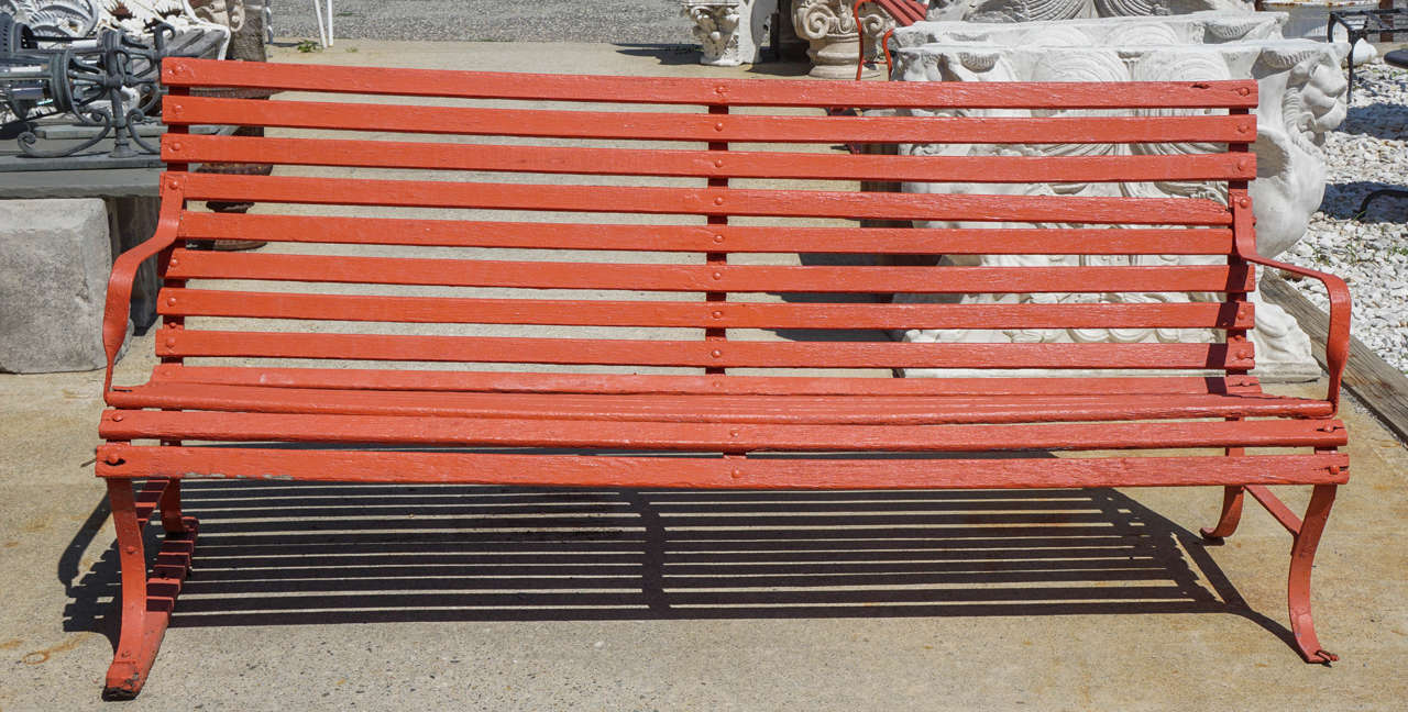 Painted bright red, the outdoor bench with arms can seat three adults or four children. The slats have a spring to them for greater comfort.

Measures: Arm height 21.50