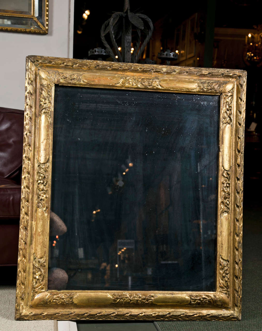 French Regence carved and gilt wood frame with a later mirror. With original gilding, some red bol showing through, giving it a warm patina.