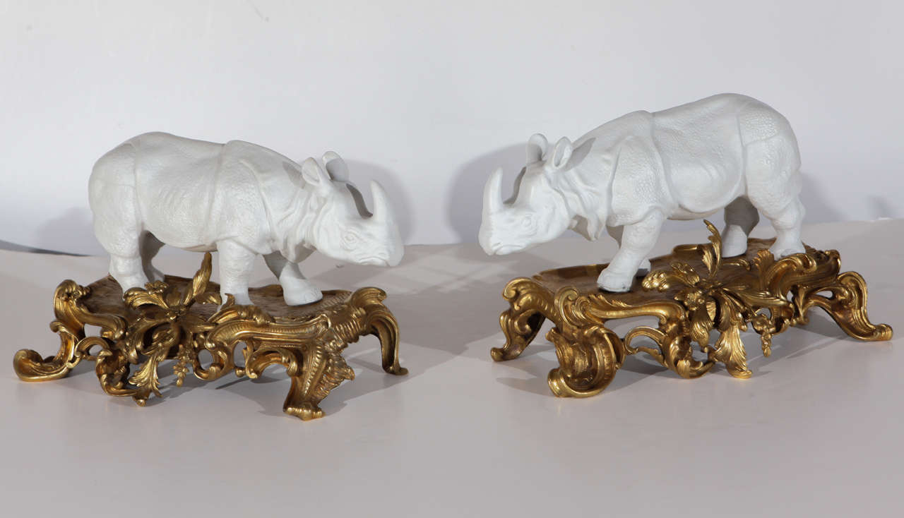 Pair of hand-cast, French bisque porcelain rhinoceros sculptures on gilt bronze, Louis XV style bases.