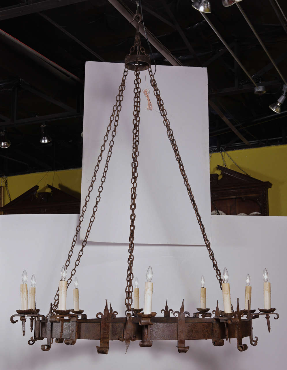 Imposing 19th Century hand-forged wrought iron chandelier suspended by original chain. The fixture is decorated with fleur-de-lys between the lights. Wiring and was candle sleeves are new.  Finish is original.