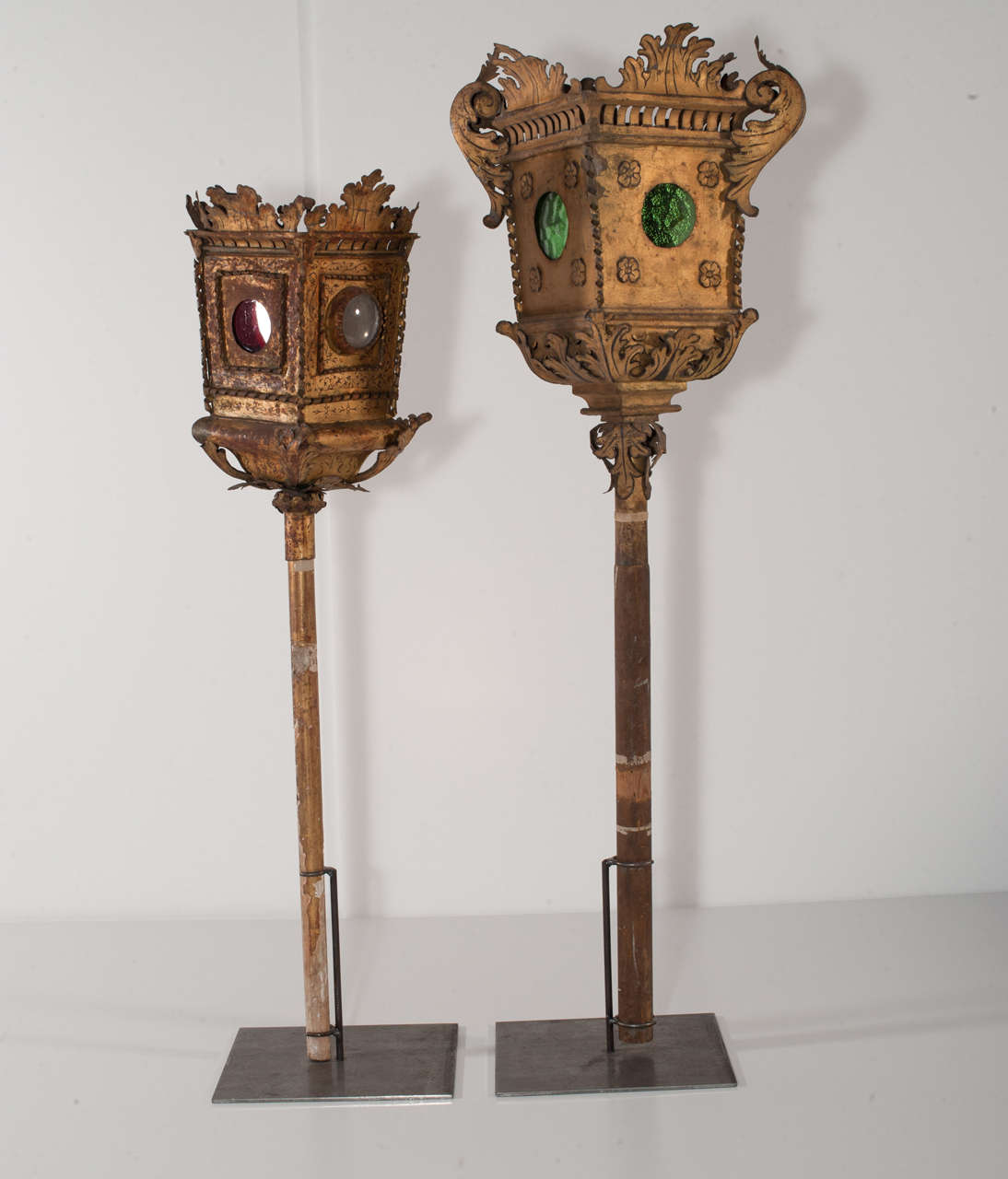 18th century pair of golden plate lanterns mounted on an iron base.

Measures: lantern with green glasses height 90cm, diameter 25cm; lantern with red glasses height 75cm, diameter 18cm.
