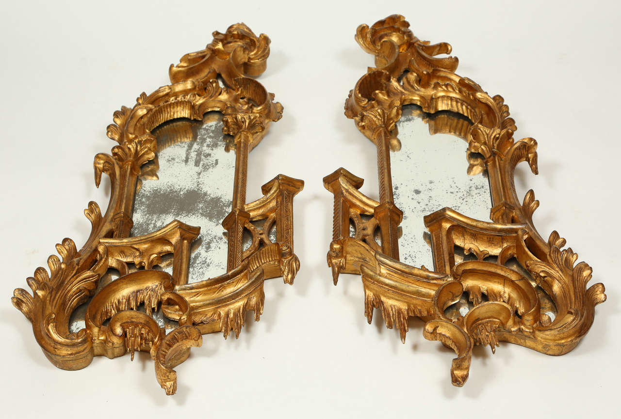 Pair of book-matched Italian gilded mirrors. Asymmetrical in the Rococo style with C and S scrolls and acanthus details throughout.  Originally used as girandoles, the candle arms are no longer present.