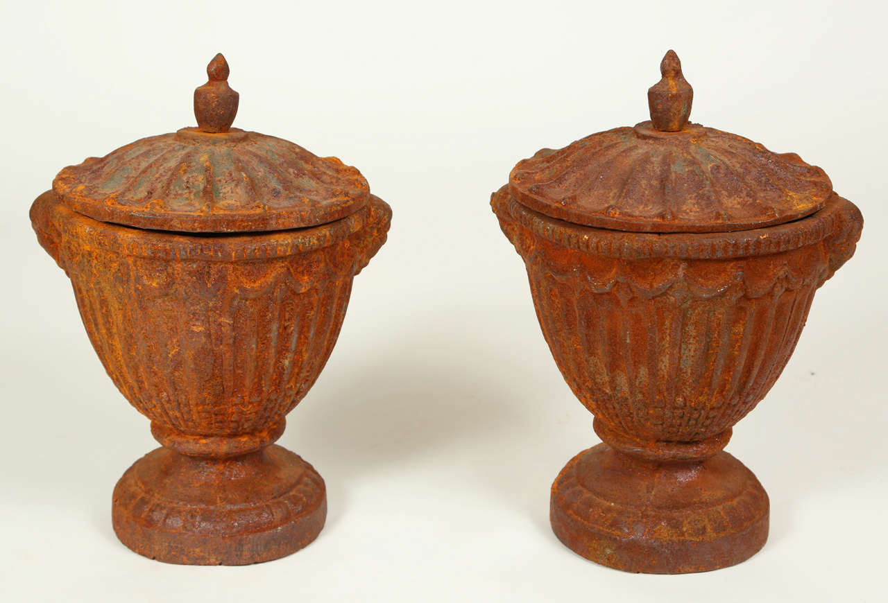 Pair of naturally distressed, vintage urns with lids. Iron has acquired a lovely, rusted patina over time.