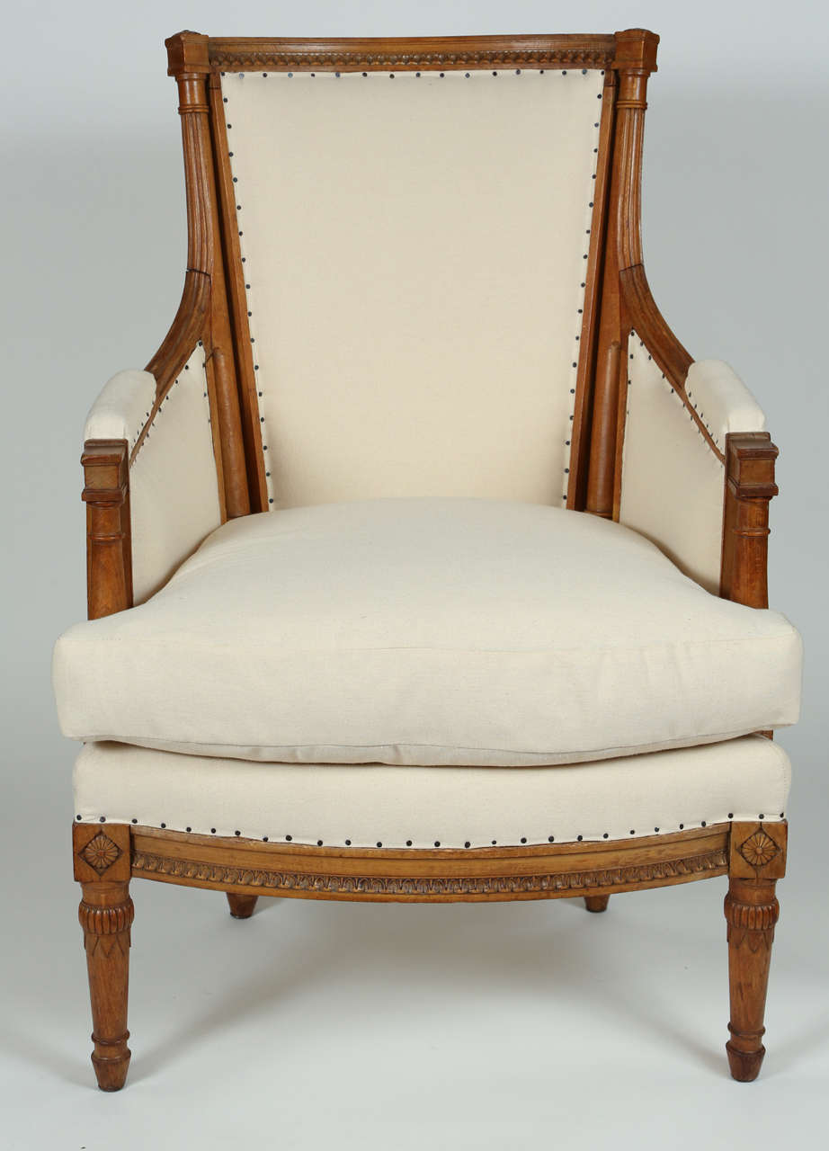 Pair of French Directoire style bergeres. Details include rosettes, fluting and turned legs. Lovely meander detail on the top rail and seat rail. Newly upholstered in muslin, circa 1930s-1940s.