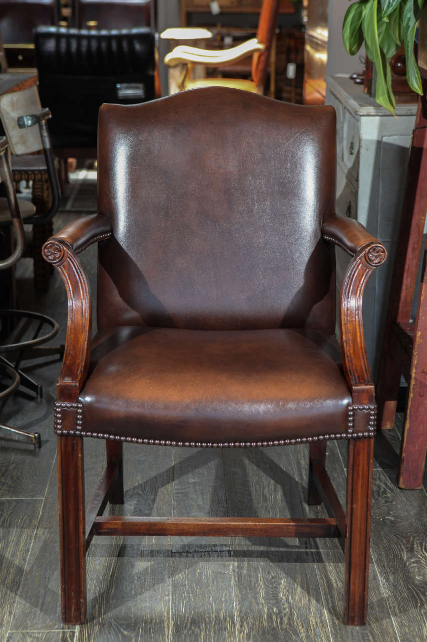A pair of Georgian Revival Gainsborough armchairs upholstered in leather.