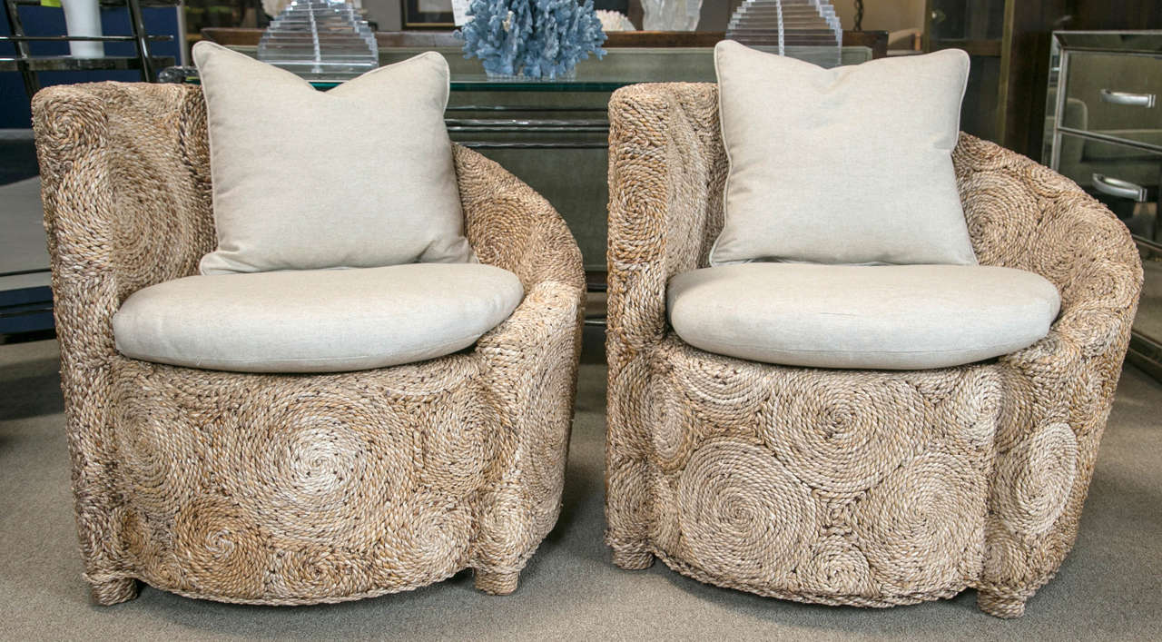 Pair of twisted rope armchairs with a curved back and asymmetrical design. New cushions, rope has been treated for durability and the frame of chair is wood. Completely covered by rope.