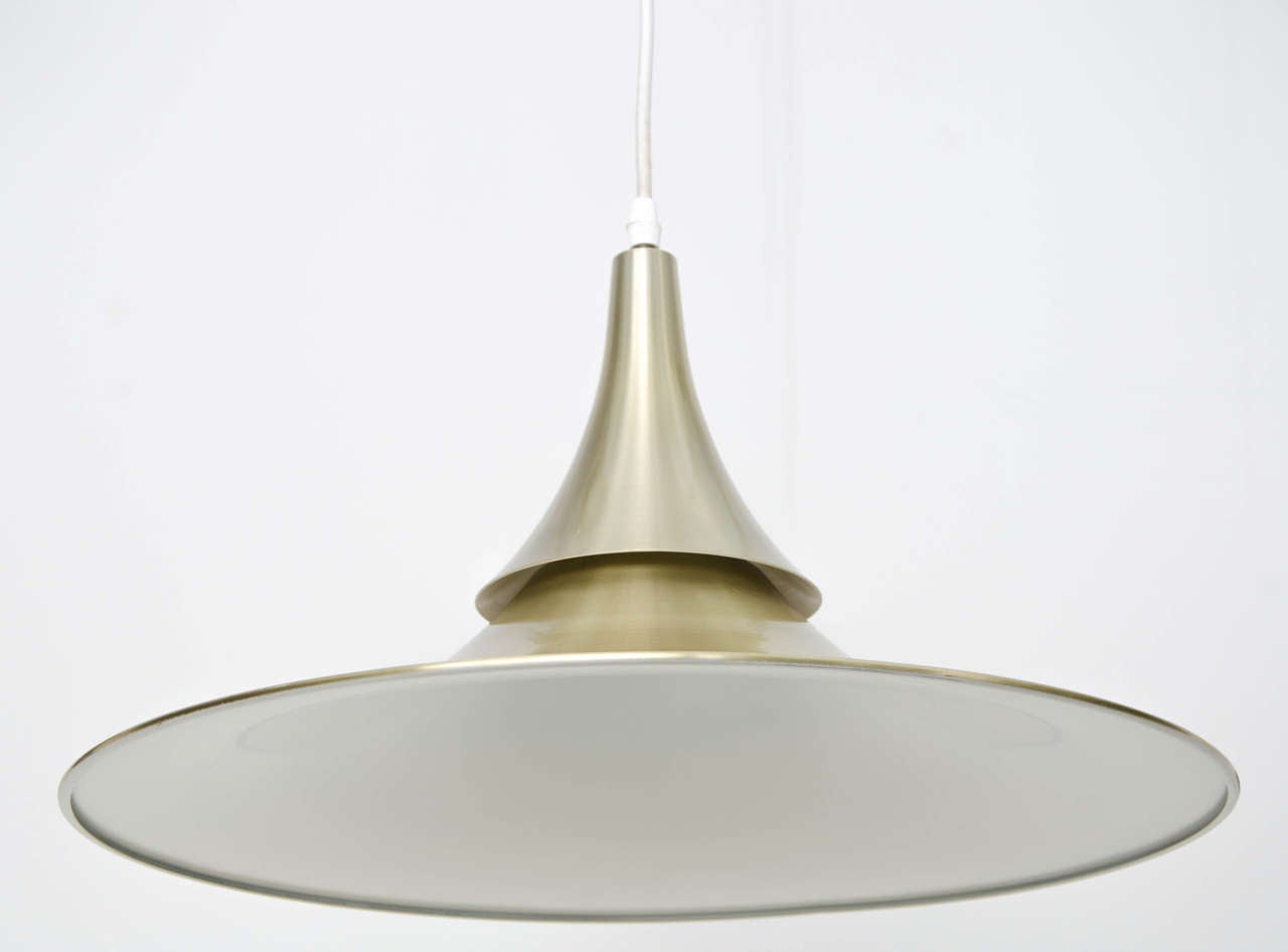 Scandinavian Modern pendant light with brass finish.  A stylish piece with clear influence of the geometry of the "Semi" by Bonderup and Thorup.  

Spun aluminium with brass finish and white interior; a nicely made lamp. The shade is