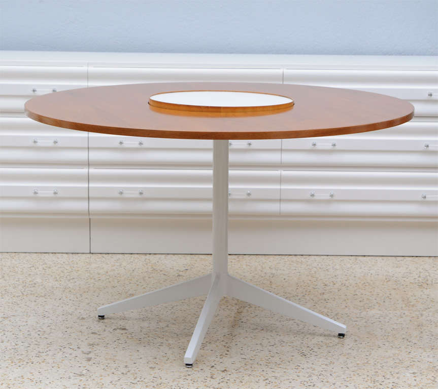 Round walnut dining table features white enameled metal legs and a white formica-topped, spinning 