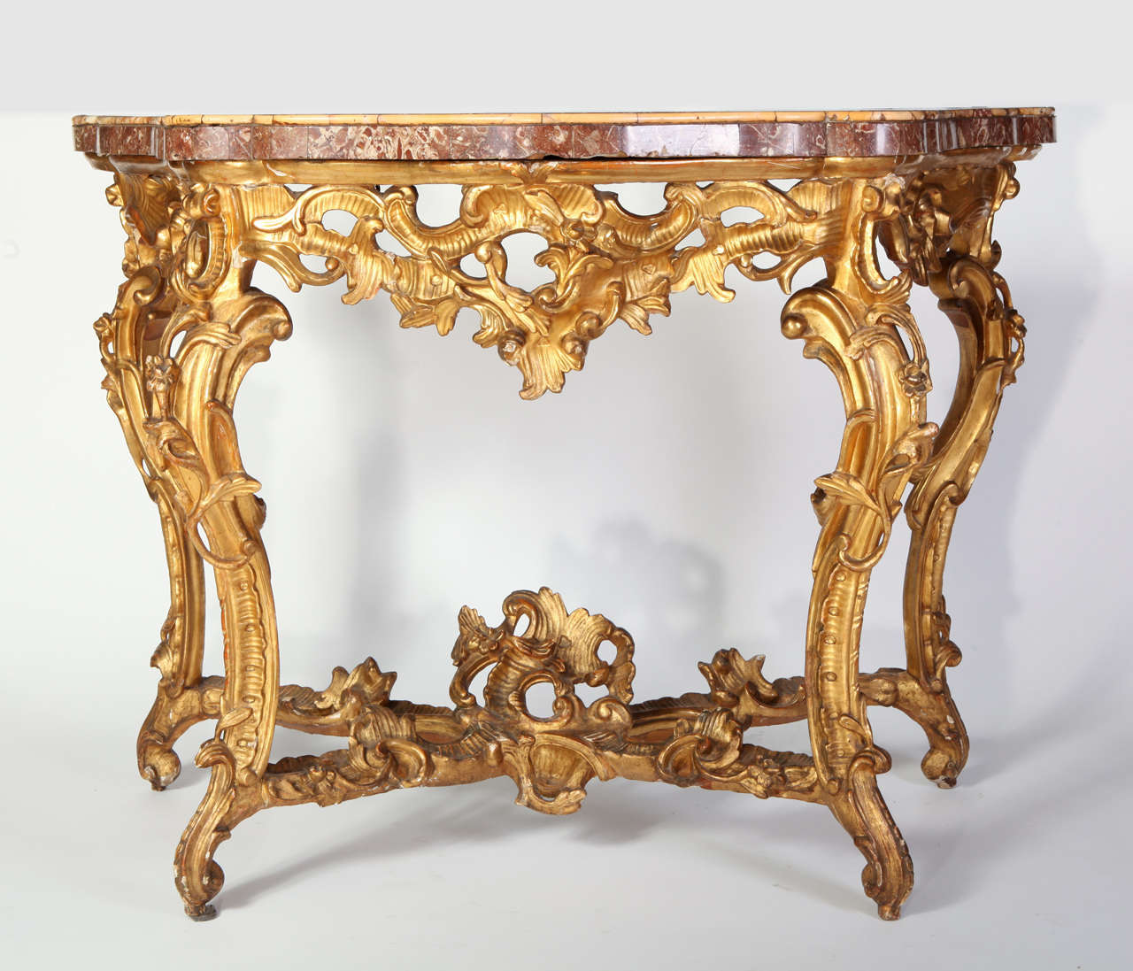 A fine pair of Roman mid-18th century giltwood Rococo consoles
each with a serpentine red Lumachella veneered marble top within a Sienna yellow marble surround, above a pierced frieze centred by a foliate cartouche, on cabriole legs with scrolling