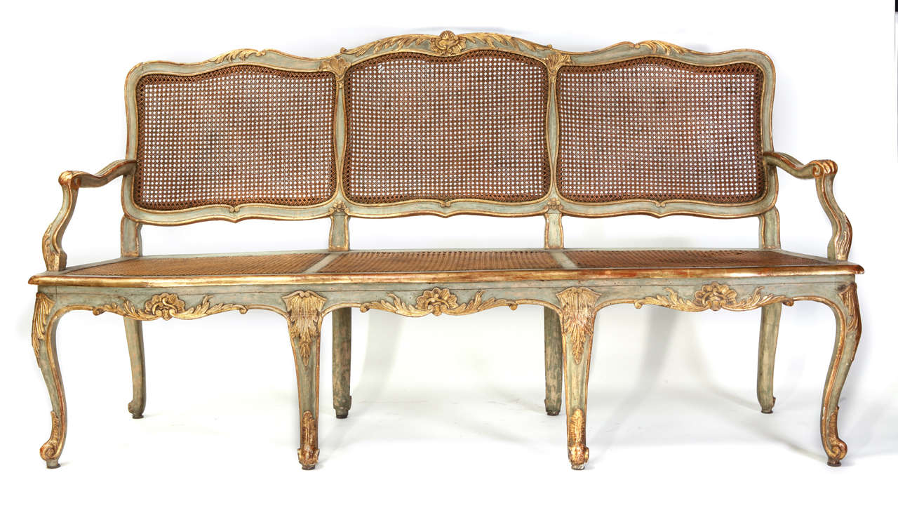 A fine Italian 18th century parcel-gilt and turquoise painted caned canape with a shaped back decorated with shell-carved crest, scrolling armrests on a serpentine seat on cabriole legs ending in scroll feet.