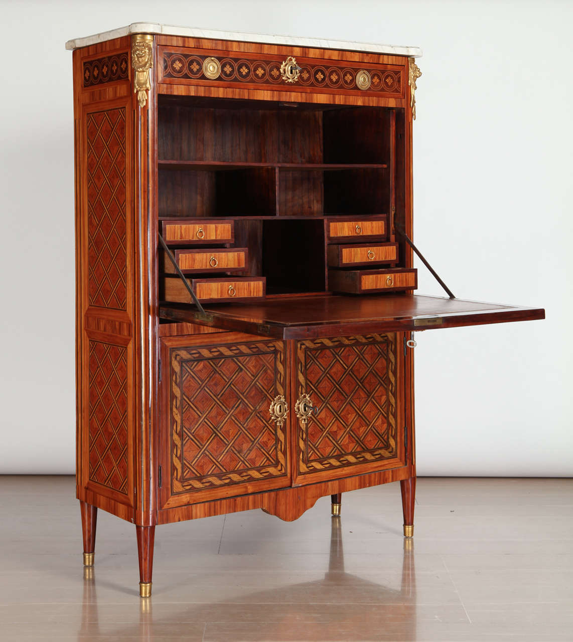 A fine French ormolu-mounted, kingwood , tulipwood and stained sycamore marqueterie and parquetry secretaire abattant with rectangular moulded white marble top , above a frieze drawer inlaid with flower heads , fall front enclosing a leather-lined