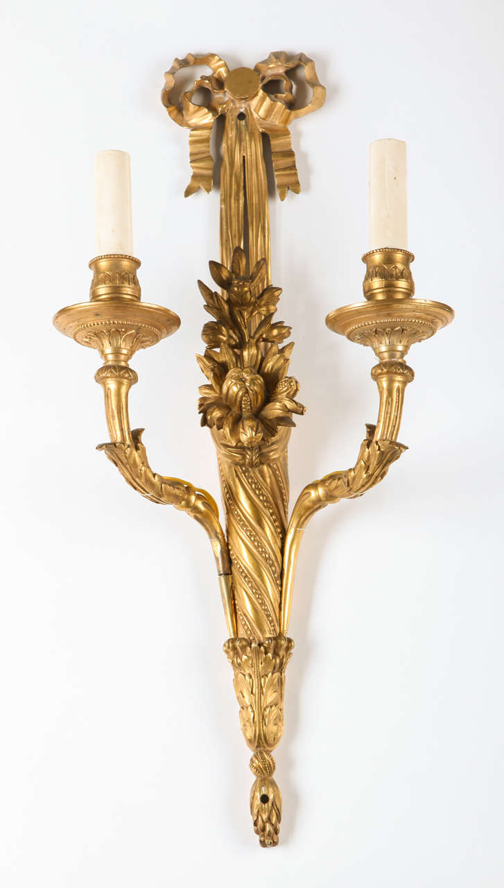 A pair of French, 18th century Louis XVI ormolu two-arm wall-lights, with a knotted drap above scrolling arms with acanthus leaves and flowers.