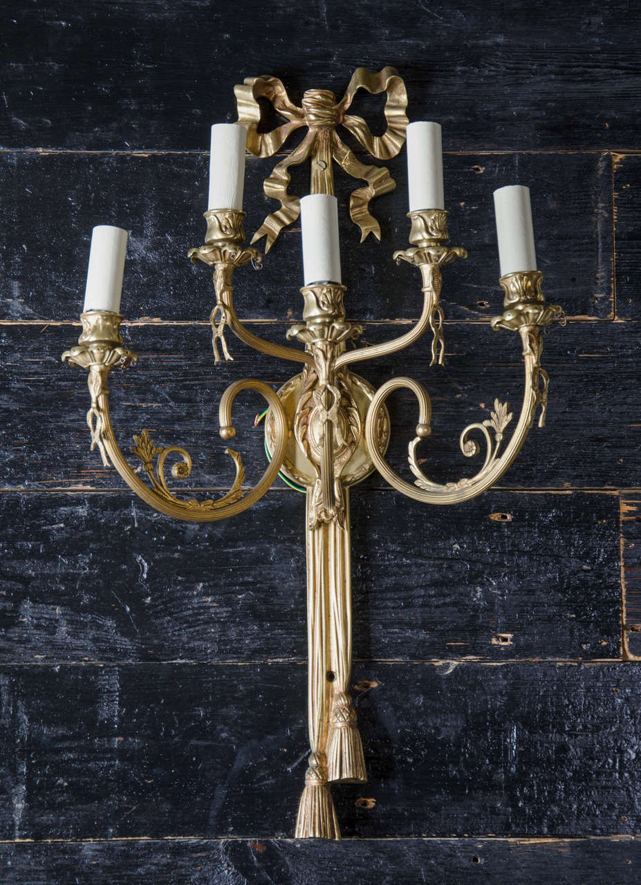 A magnificent pair of large brass sconces with exceptional decorative detail. These large, impressive sconces are in the neoclassical Adams style. They each have five scrolling, reeded branches topped with petal-shaped drip pans and shell motifs