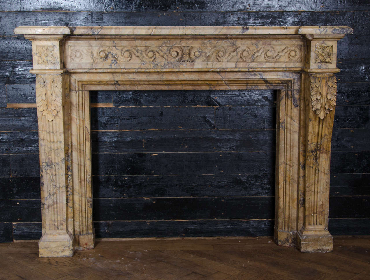 An exceptional and outstanding fire surround carved entirely from Sienna marble. This antique Louis XVI surround features a reflected vitruvian scroll running along the frieze, flanked by two pronounced endblocks decorated with a finely carved oak