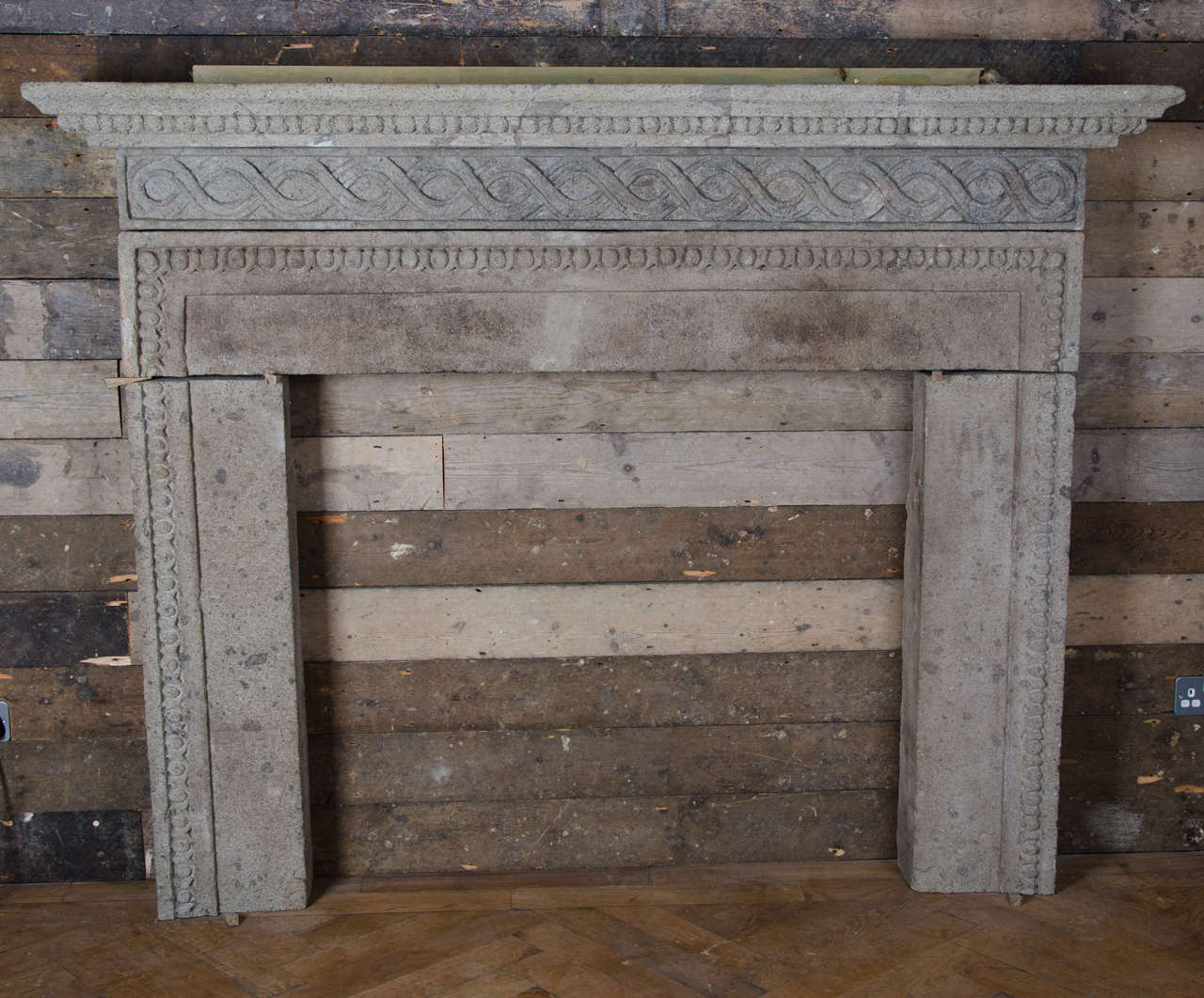 An impressive and imposing carved stone fireplace surround in the Italian Renaissance manner. This antique surround has a characterful weathered finished and features a carved egg and dart trim around the opening and a guilloche decoration on the