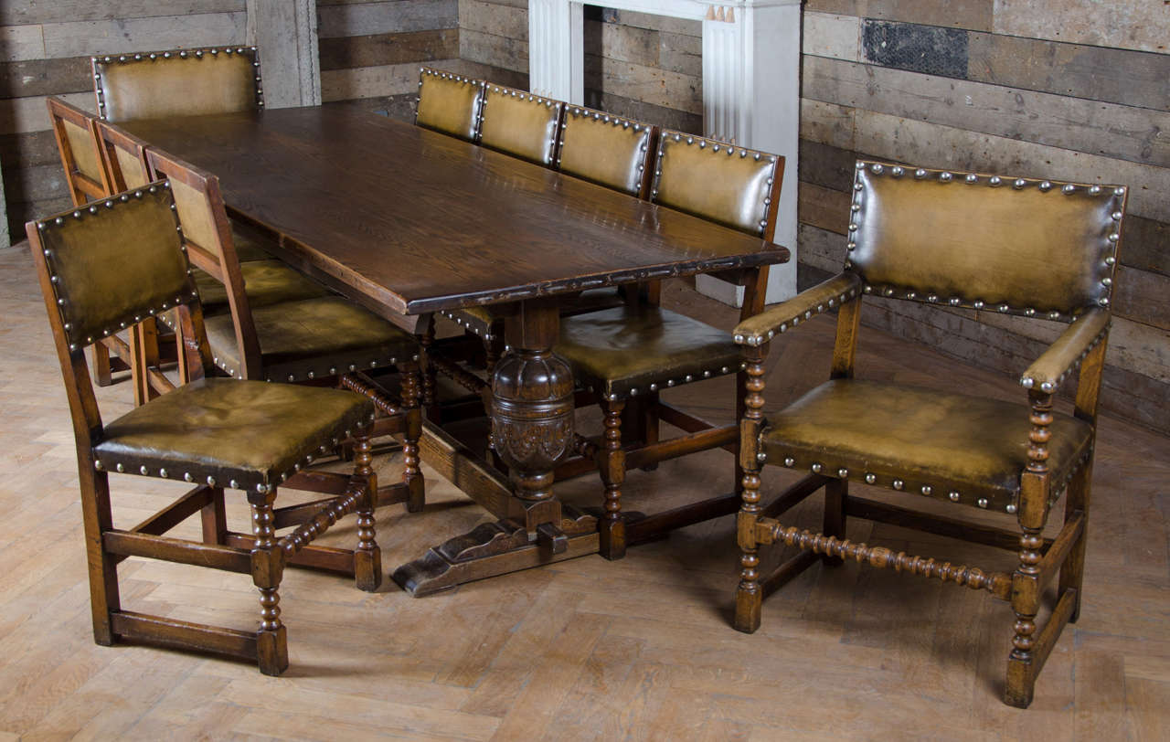 A wonderful original dining set in very good condition, dating from the 1920s. This solid oak refectory table and dining chairs set has a rich, dark finish which suites the style of the set well. The chairs are upholstered in green leather with