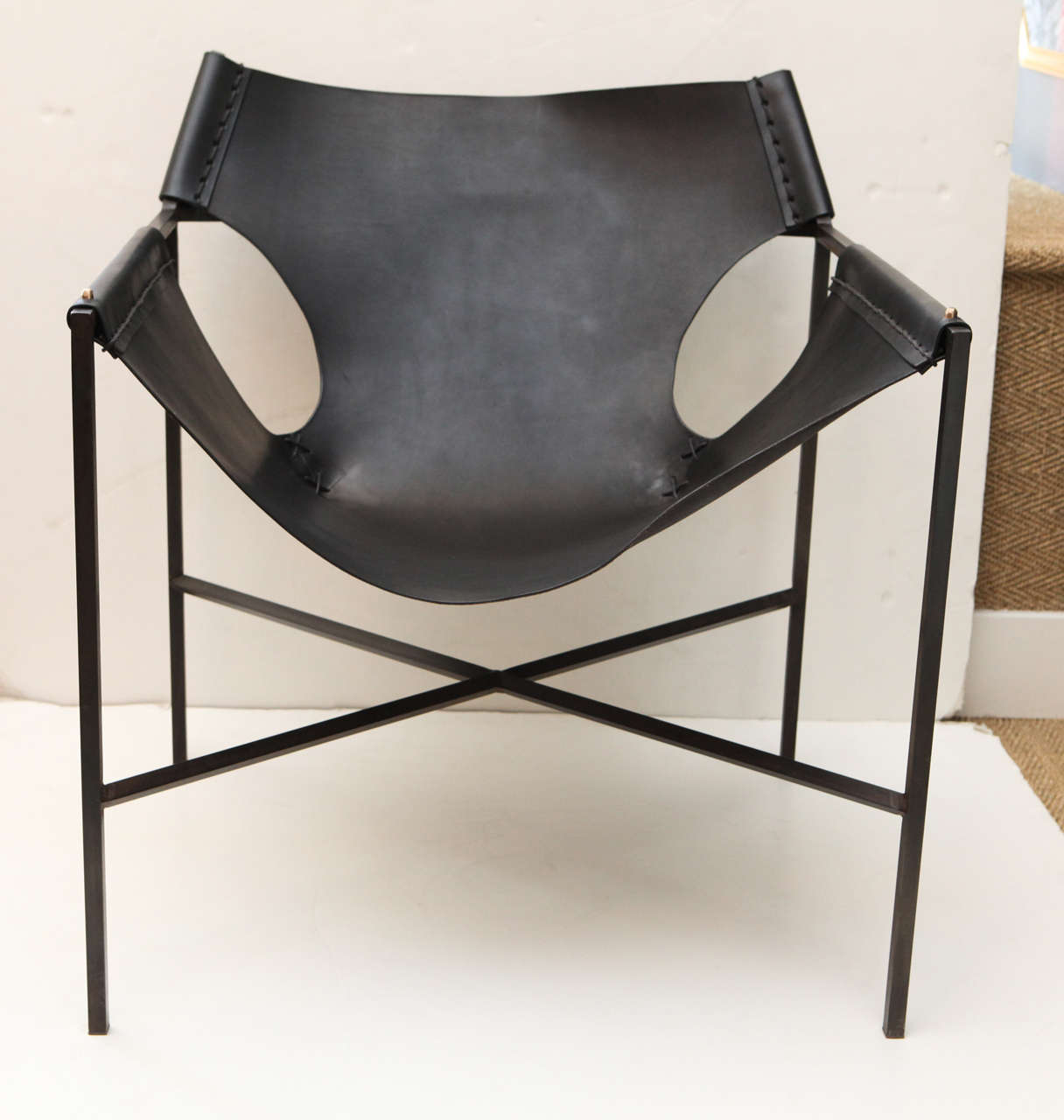 Steel and leather, x-based sling chair featuring wet-formed darted corners and hammered bronze rivets. Hand-cut leather is vegetable tanned with a waxed finish.