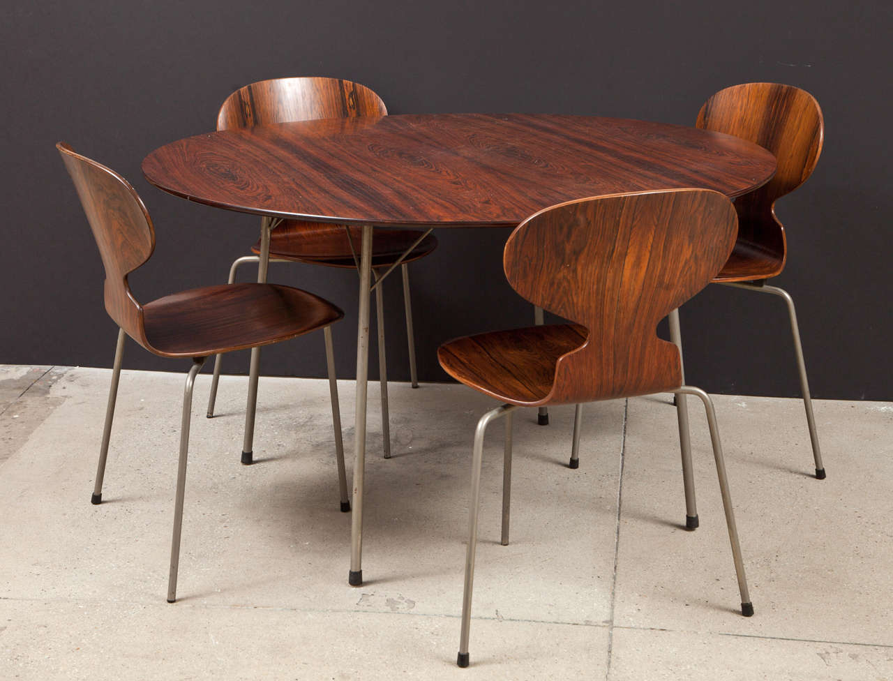 A matching set of four dining chairs and a round table in Rosewood with steel lets.  Designed by Arne Jacobsen for Fritz Hansen.  Signed.  Denmark, circa 1960.

Features the Model 3600 dining table and Model 3101 chair.