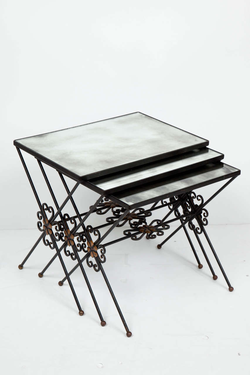 Set of three French Moderne wrought iron nesting tables with gilt accents and original silvered mercury glass mirror tops.