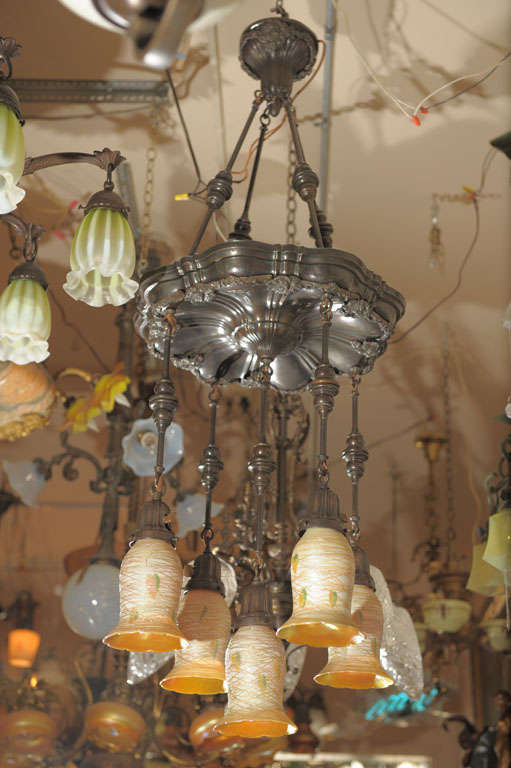 This chandelier hangs so gracefully it will make an entryway or dining room come to life. Rich, dark brown patina on the metal creates a warm glow and the shades are top of the line heart and vine style and signed by 